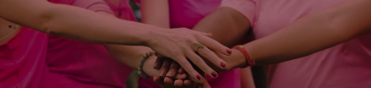 Mulheres unidas com as mãos umas sobre a outras